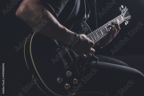 a guy in a dark T-shirt plays an electric guitar on a dark background