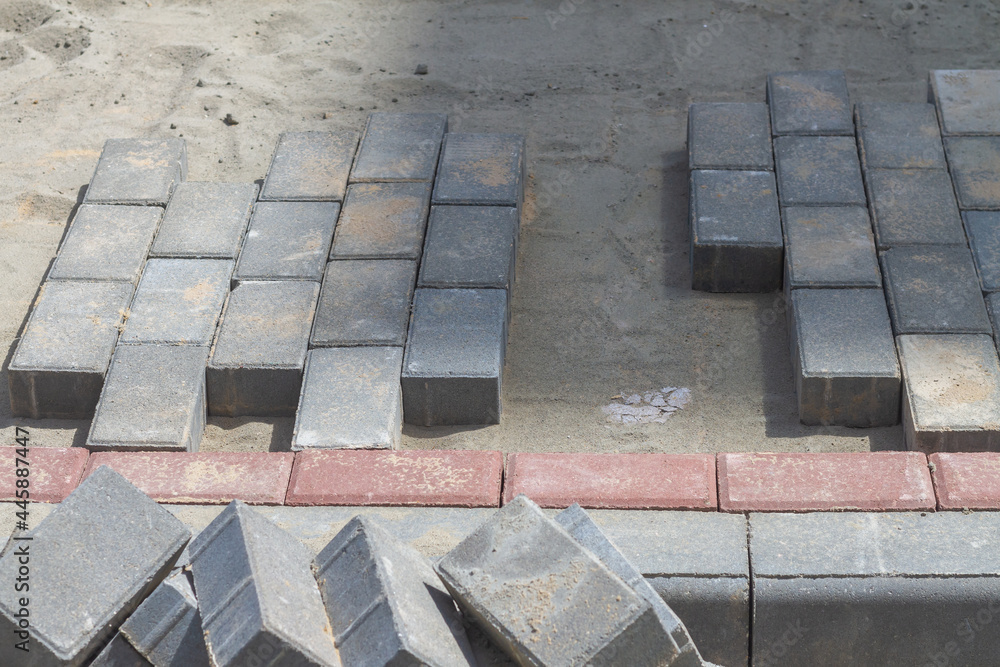Workers lay out paving slabs on the sidewalk near a residential building Workers lay out paving slabs on the sidewalk near a residential building
