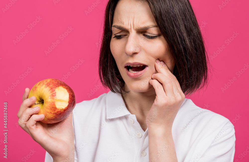 Beautiful young woman bites a big apple and has a toothache Beautiful young woman bites a big apple and has a toothache