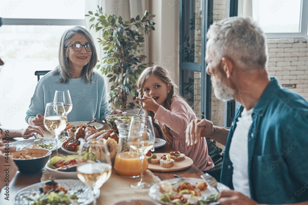 Beautiful multi-generation family communicating and smiling while having dinner together