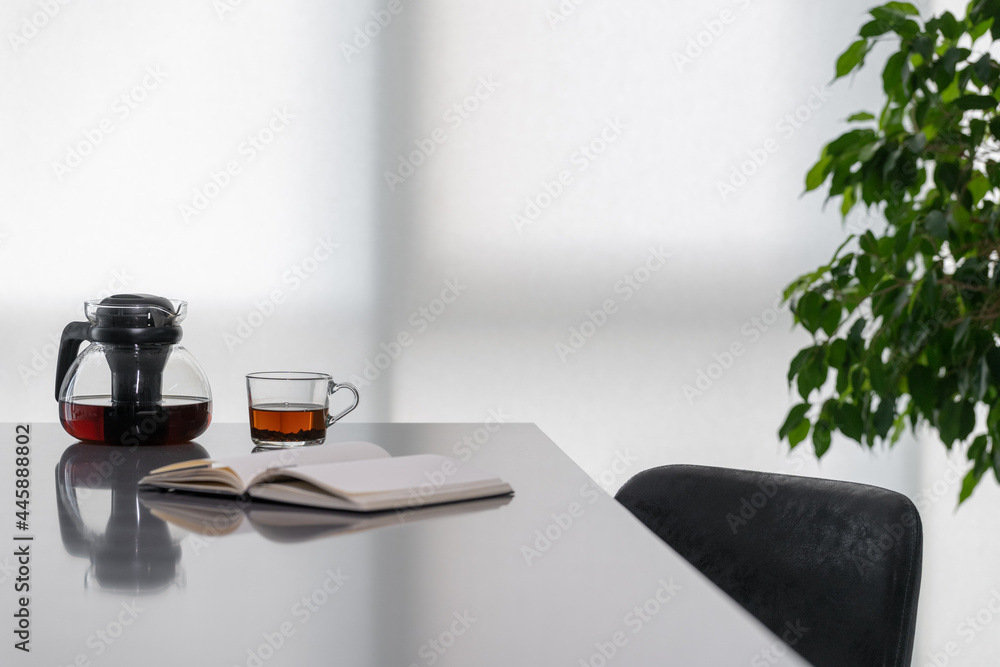 Notebook, cup of tea with teapot on table - obrazy, fototapety, plakaty 