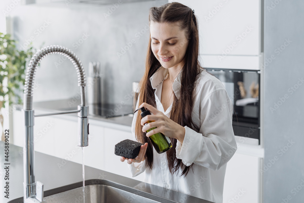 Smiing woman housewife cleaning dishes in sink Smiing woman housewife cleaning dishes in sink
