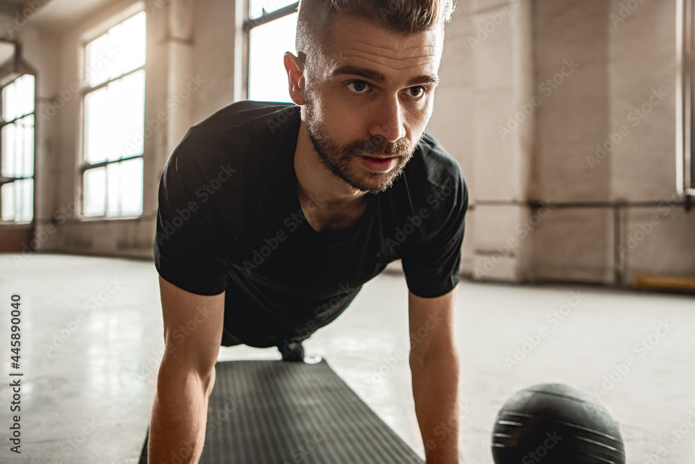 Fototapeta premium Serious man doing plank exercise in gym