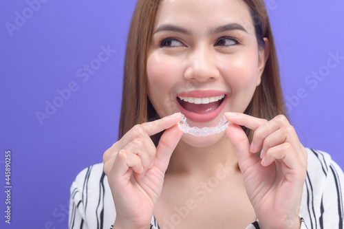 Young smiling woman holding invisalign braces in studio, dental healthcare and Orthodontic concept..