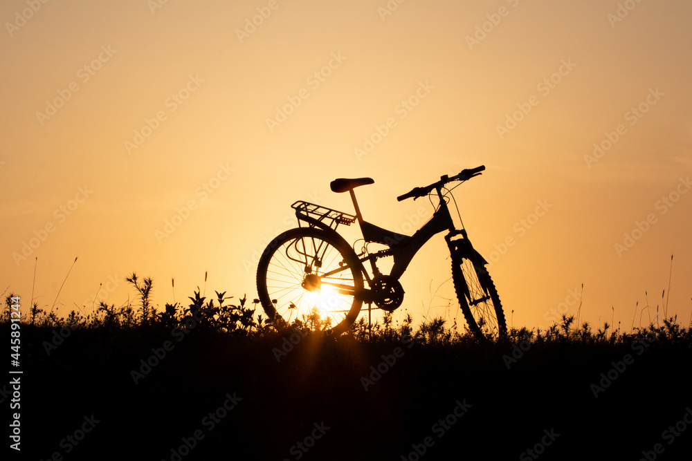 Mountains bike silhouette and setting sun, orang sunset.