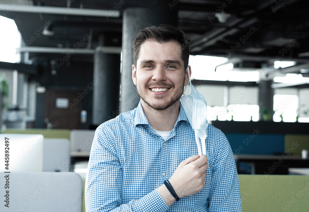 Obraz premium Businessman taking his medical protective mask off while working in the office