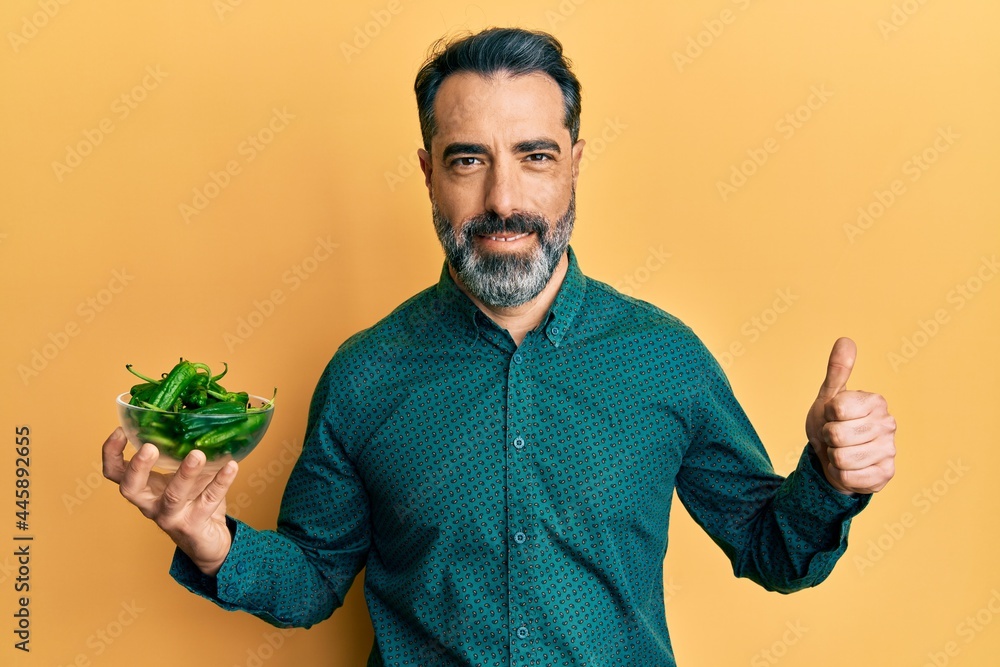 Middle age man with beard and grey hair holding green apples smiling happy and positive, thumb up doing excellent and approval sign Middle age man with beard and grey hair holding green apples smiling happy and positive, thumb up doing excellent and approval sign