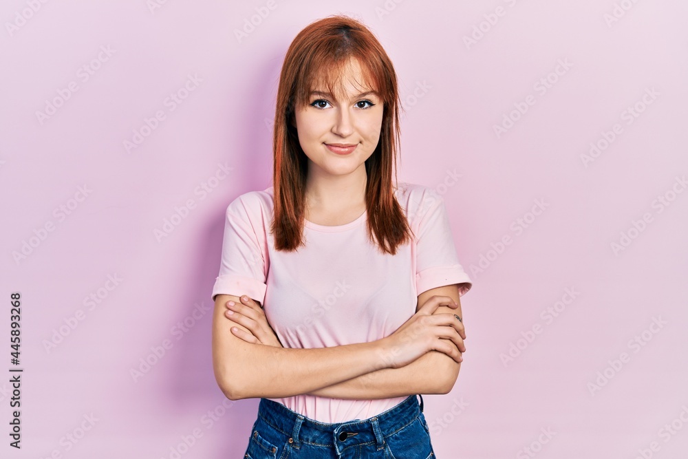 Redhead young woman wearing casual pink t shirt happy face smiling with crossed arms looking at the camera. positive person. Redhead young woman wearing casual pink t shirt happy face smiling with crossed arms looking at the camera. positive person.