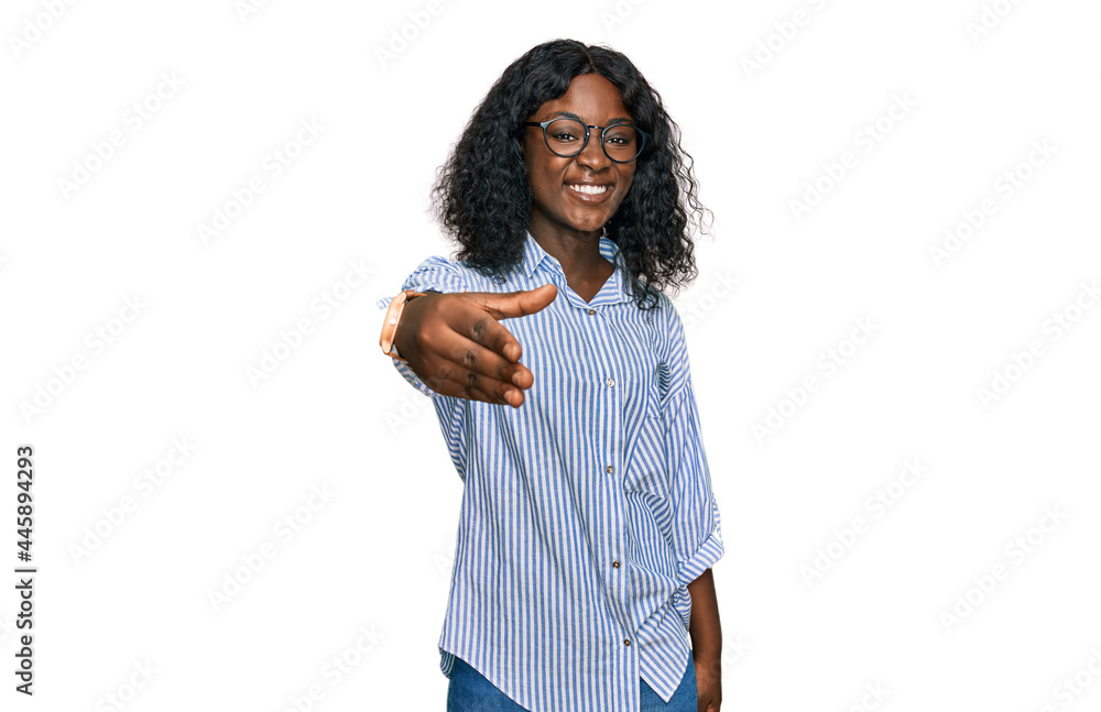 Beautiful african young woman wearing casual clothes and glasses smiling friendly offering handshake as greeting and welcoming. successful business. Beautiful african young woman wearing casual clothes and glasses smiling friendly offering handshake as greeting and welcoming. successful business.