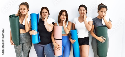 Group of women holding yoga mat standing over isolated background touching mouth with hand with painful expression because of toothache or dental illness on teeth. dentist concept.