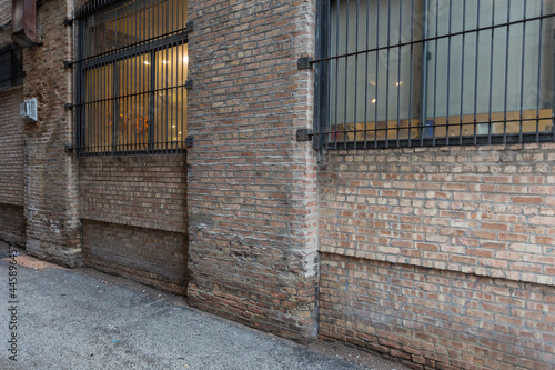 Angle view of vintage brick building and alleyway with barred windows in urban setting © Richard