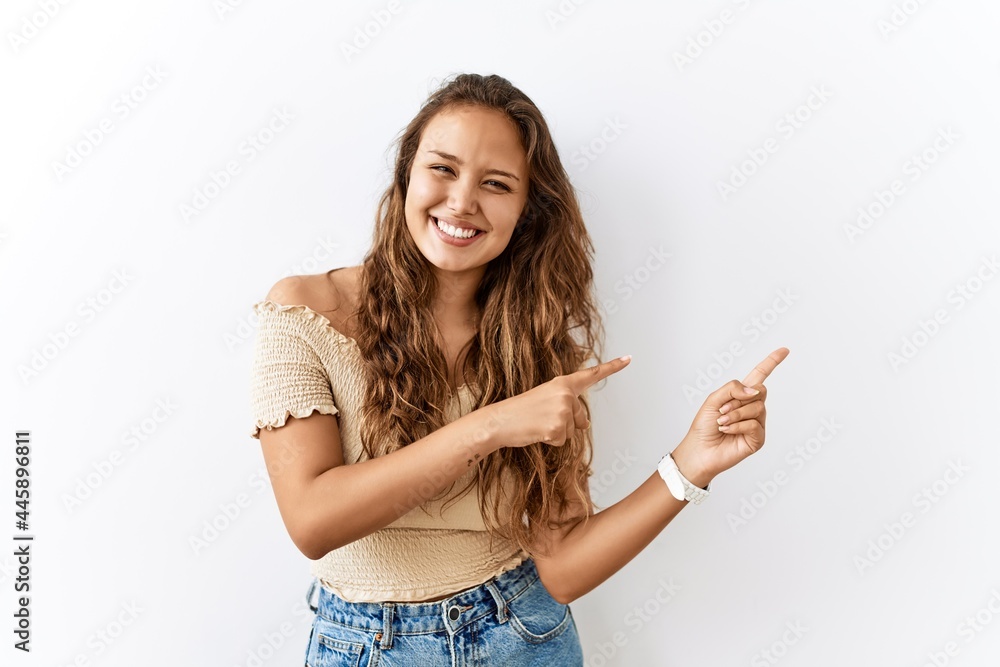 Beautiful hispanic woman standing over isolated while background smiling and looking at the camera pointing with two hands and fingers to the side. Beautiful hispanic woman standing over isolated while background smiling and looking at the camera pointing with two hands and fingers to the side.
