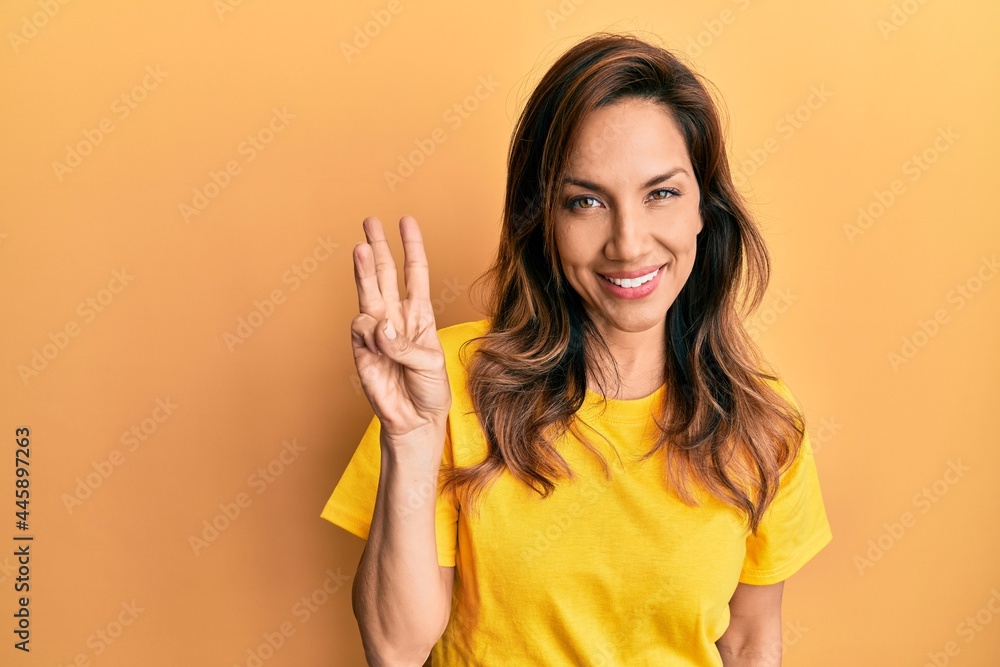 Young latin woman wearing casual clothes showing and pointing up with fingers number three while smiling confident and happy. Young latin woman wearing casual clothes showing and pointing up with fingers number three while smiling confident and happy.