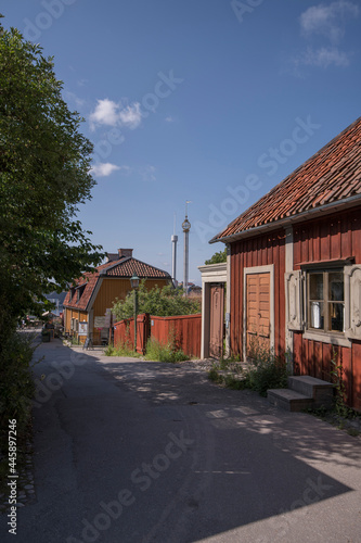 Street view with old wooden houses in a Stockholm park with amusement park towers in the 
background