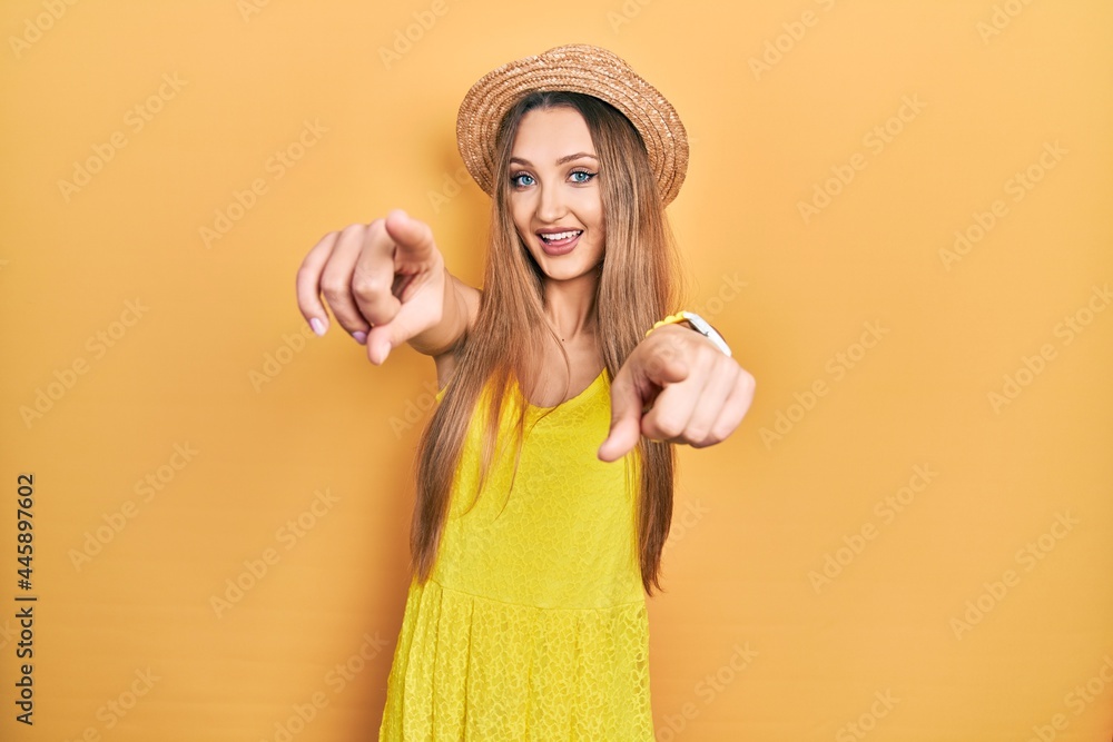 Young blonde girl wearing summer hat pointing to you and the camera with fingers, smiling positive and cheerful Young blonde girl wearing summer hat pointing to you and the camera with fingers, smiling positive and cheerful
