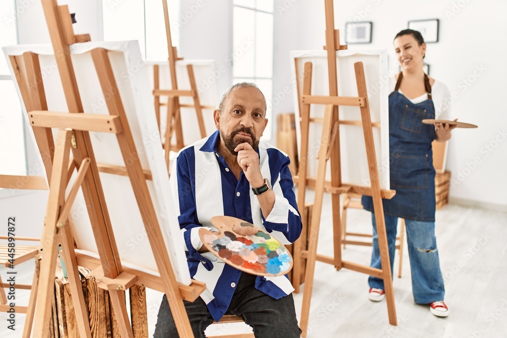 Senior artist man at art studio with hand on chin thinking about question, pensive expression. smiling and thoughtful face. doubt concept.