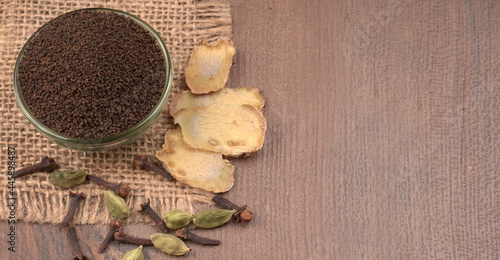 Fototapeta Naklejka Na Ścianę i Meble -  Black Tea Powder or dry dust tea powder, chai patti isolated in wooden bowl with Cardamom, Clove and Ginger.