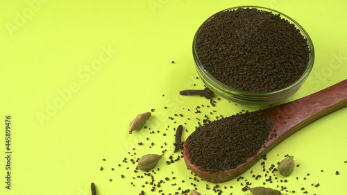 Black Tea Powder or dry dust tea powder, chai patti isolated in wooden bowl with Cardamom, Clove and Ginger.