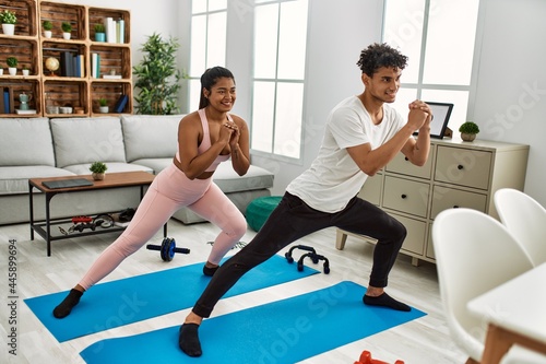 Young latin sporty couple smiling happy training at home.