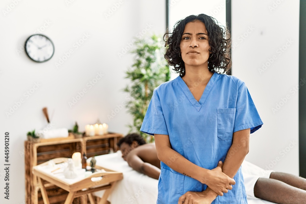 Young therapist woman at wellness spa center smiling looking to the side and staring away thinking. Young therapist woman at wellness spa center smiling looking to the side and staring away thinking.