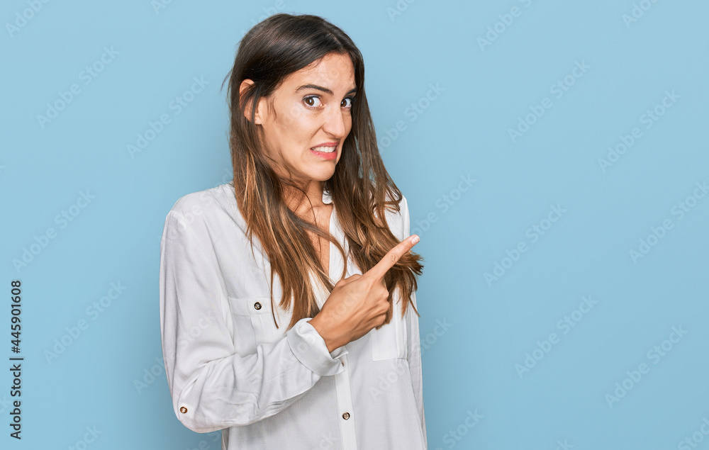 Young beautiful woman wearing casual clothes pointing aside worried and nervous with forefinger, concerned and surprised expression Young beautiful woman wearing casual clothes pointing aside worried and nervous with forefinger, concerned and surprised expression