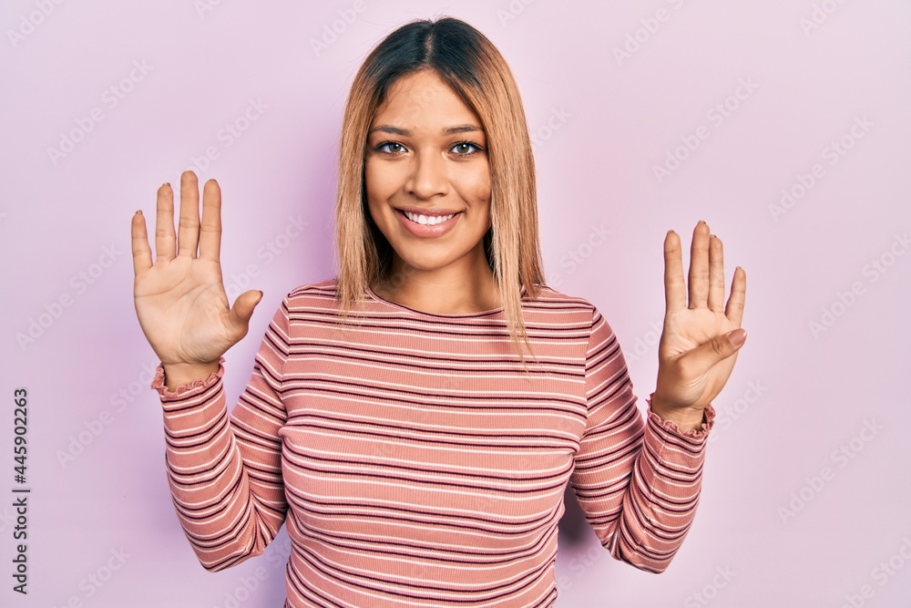 Beautiful hispanic woman wearing casual striped sweater showing and pointing up with fingers number nine while smiling confident and happy. Beautiful hispanic woman wearing casual striped sweater showing and pointing up with fingers number nine while smiling confident and happy.