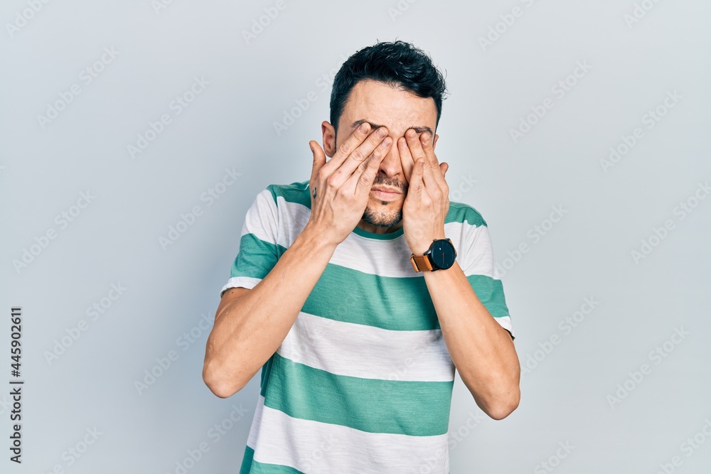 Young hispanic man wearing casual clothes rubbing eyes for fatigue and headache, sleepy and tired expression. vision problem Young hispanic man wearing casual clothes rubbing eyes for fatigue and headache, sleepy and tired expression. vision problem