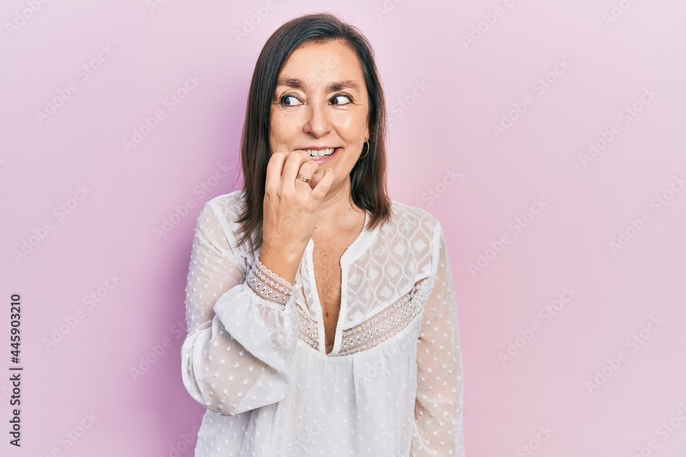 Middle age hispanic woman wearing casual clothes looking stressed and nervous with hands on mouth biting nails. anxiety problem. Middle age hispanic woman wearing casual clothes looking stressed and nervous with hands on mouth biting nails. anxiety problem.