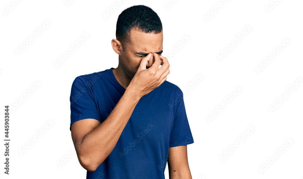 Young african american man wearing casual t shirt tired rubbing nose and eyes feeling fatigue and headache. stress and frustration concept. Young african american man wearing casual t shirt tired rubbing nose and eyes feeling fatigue and headache. stress and frustration concept.