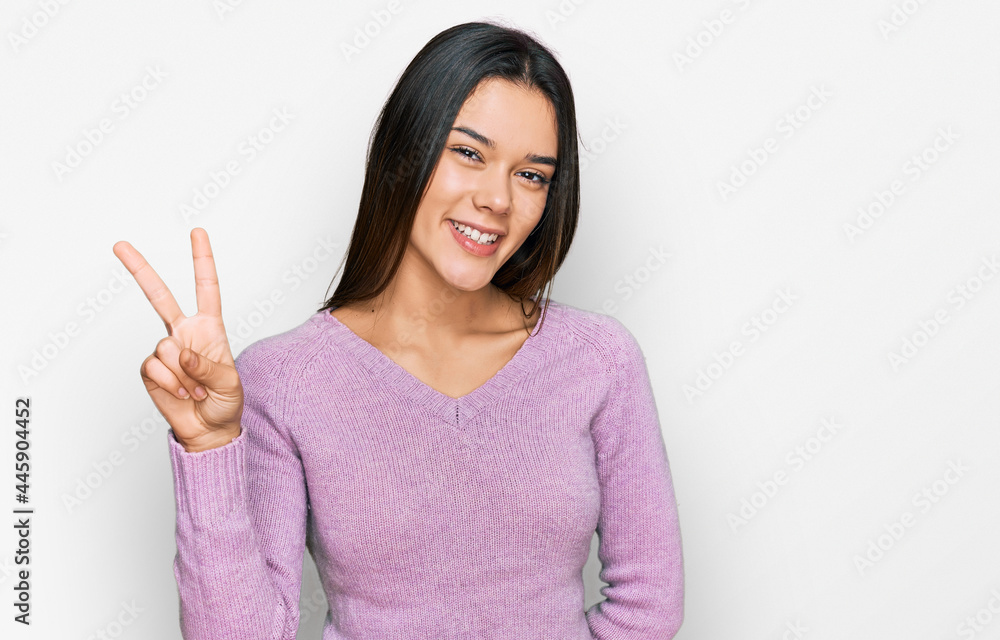 Young hispanic girl wearing casual clothes showing and pointing up with fingers number two while smiling confident and happy. Young hispanic girl wearing casual clothes showing and pointing up with fingers number two while smiling confident and happy.