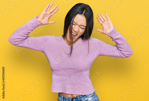 Young hispanic girl wearing casual clothes celebrating mad and crazy for success with arms raised and closed eyes screaming excited. winner concept