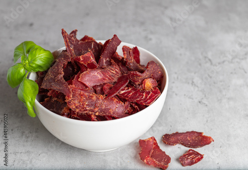 Jerky Beef, Jerky in white bowls on a concrete background. Rustic country style dried meat. Delicious meat snack.
