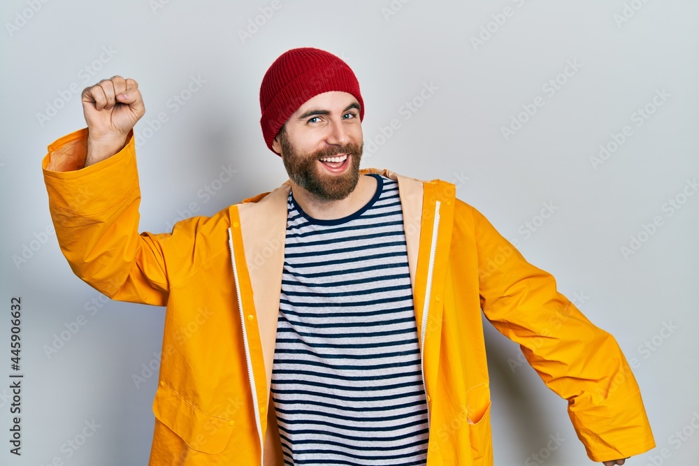 Caucasian man with beard wearing yellow raincoat dancing happy and cheerful, smiling moving casual and confident listening to music