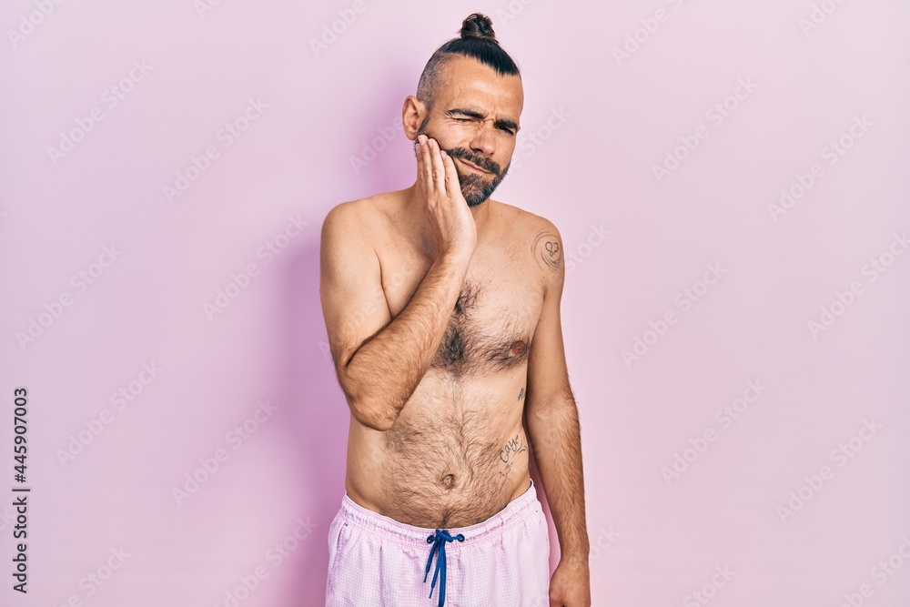 Fototapeta premium Young hispanic man shirtless wearing swimsuit touching mouth with hand with painful expression because of toothache or dental illness on teeth. dentist