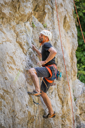 Athletic mid age man in a difficult rock climbing tour in the La Gola climbing area, Sarca Valley, Lake Garda mountains, Trentino Italy