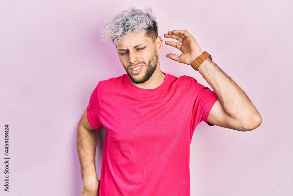 Young hispanic man with modern dyed hair wearing casual pink t shirt stretching back, tired and relaxed, sleepy and yawning for early morning Young hispanic man with modern dyed hair wearing casual pink t shirt stretching back, tired and relaxed, sleepy and yawning for early morning
