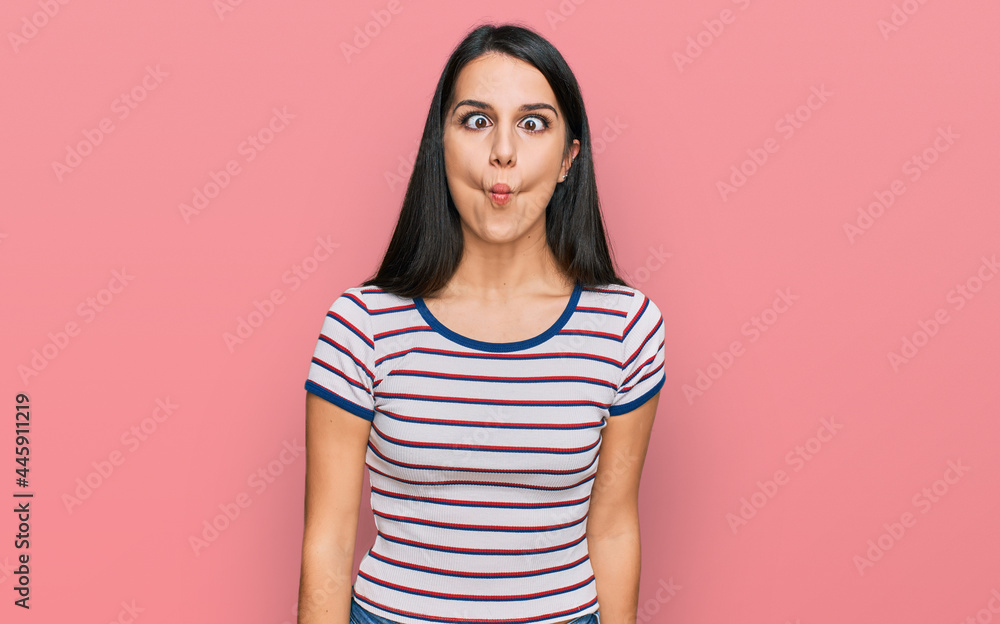 Young hispanic girl wearing casual striped t shirt making fish face with lips, crazy and comical gesture. funny expression. Young hispanic girl wearing casual striped t shirt making fish face with lips, crazy and comical gesture. funny expression.