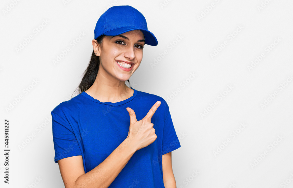 Young hispanic girl wearing delivery courier uniform cheerful with a smile of face pointing with hand and finger up to the side with happy and natural expression on face Young hispanic girl wearing delivery courier uniform cheerful with a smile of face pointing with hand and finger up to the side with happy and natural expression on face