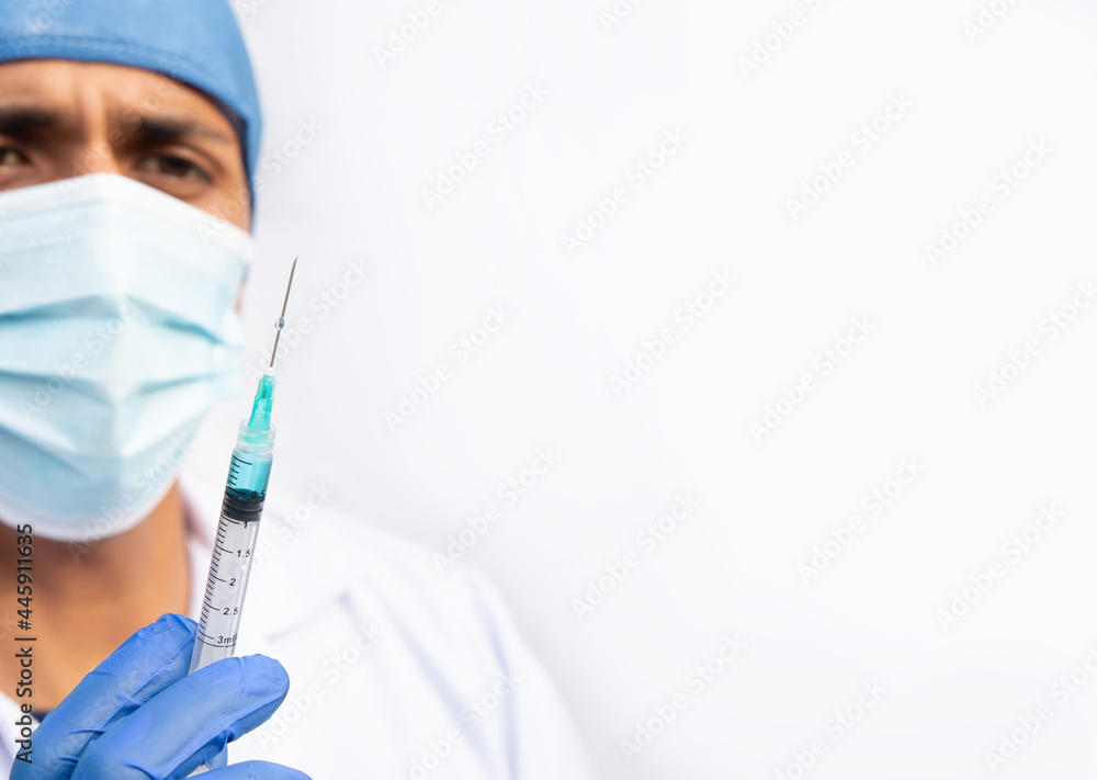 Latino doctor holding a syringe containing a blue liquid. Hispanic man on white background. Latino doctor holding a syringe containing a blue liquid. Hispanic man on white background.