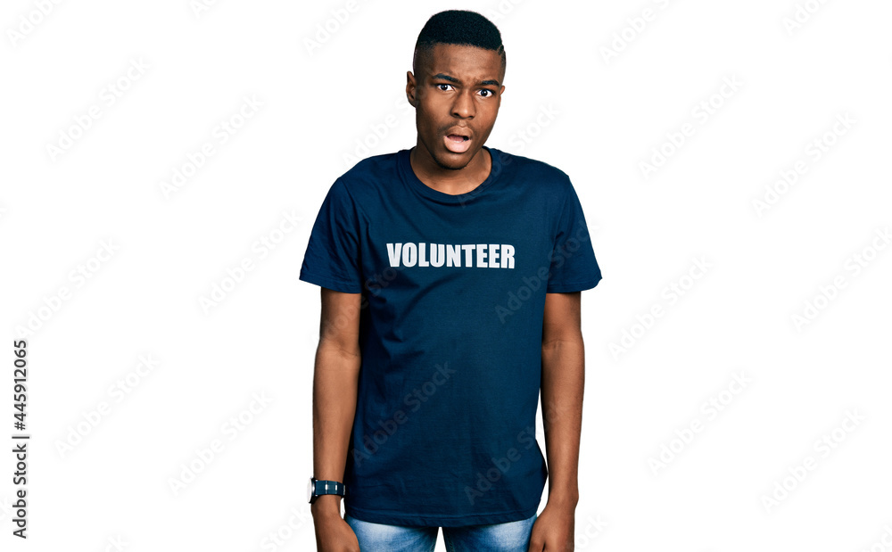 Fototapeta premium Young african american man wearing volunteer t shirt in shock face, looking skeptical and sarcastic, surprised with open mouth