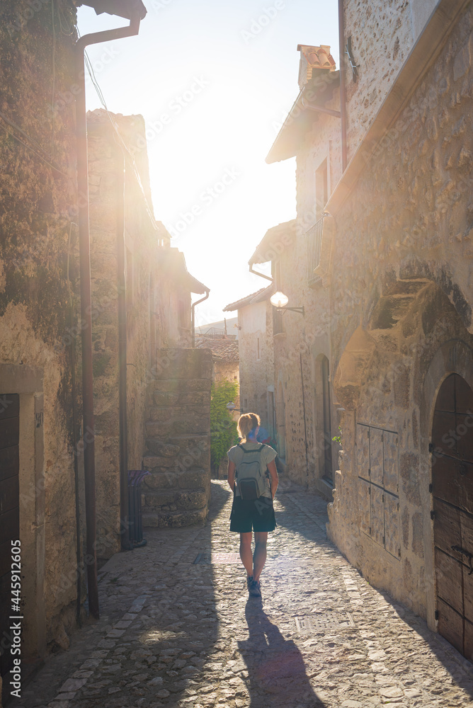 Tourist walking in Santo Stefano di Sessanio medieval village details, historical stone buildings, ancient alley, old city stone architecture. Abruzzo, Italy.