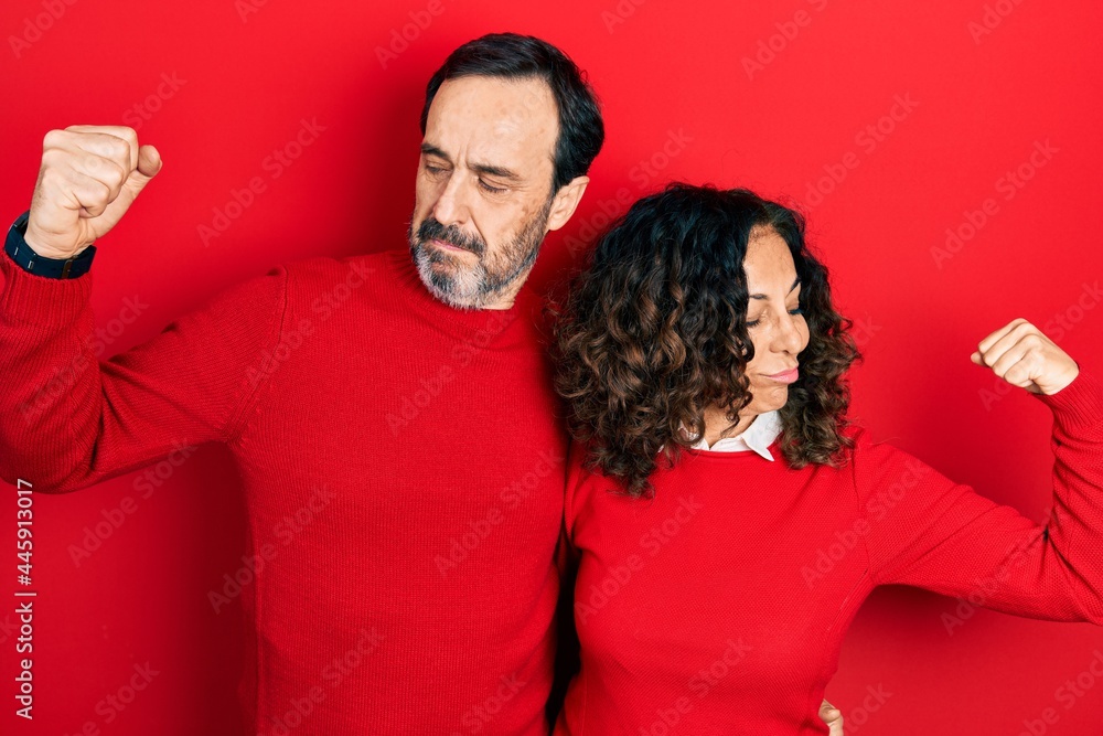 Middle age couple of hispanic woman and man hugging and standing together showing arms muscles smiling proud. fitness concept. Middle age couple of hispanic woman and man hugging and standing together showing arms muscles smiling proud. fitness concept.