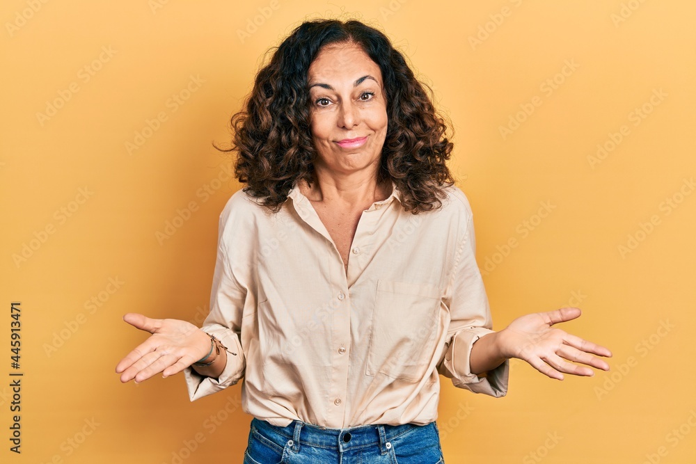 Middle age hispanic woman wearing casual clothes clueless and confused expression with arms and hands raised. doubt concept. Middle age hispanic woman wearing casual clothes clueless and confused expression with arms and hands raised. doubt concept.