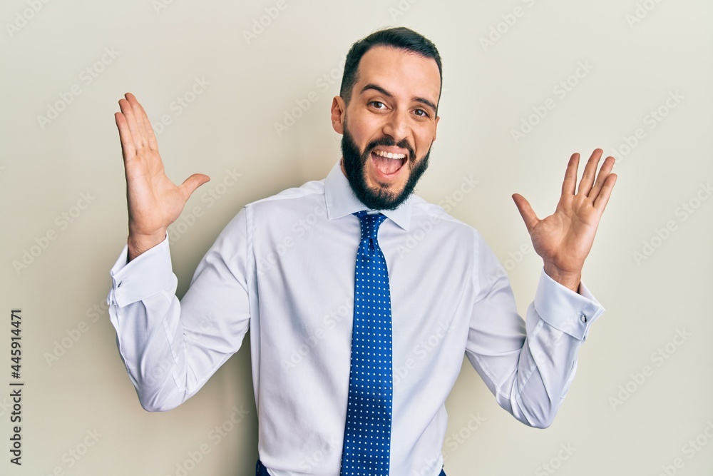 Young man with beard wearing business tie celebrating crazy and amazed for success with arms raised and open eyes screaming excited. winner concept Young man with beard wearing business tie celebrating crazy and amazed for success with arms raised and open eyes screaming excited. winner concept