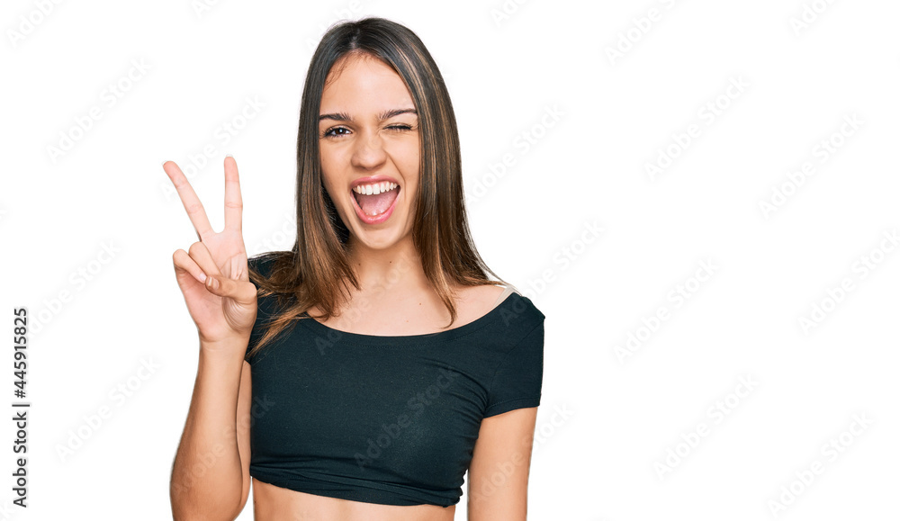 Young brunette woman wearing casual clothes smiling with happy face winking at the camera doing victory sign. number two. Young brunette woman wearing casual clothes smiling with happy face winking at the camera doing victory sign. number two.