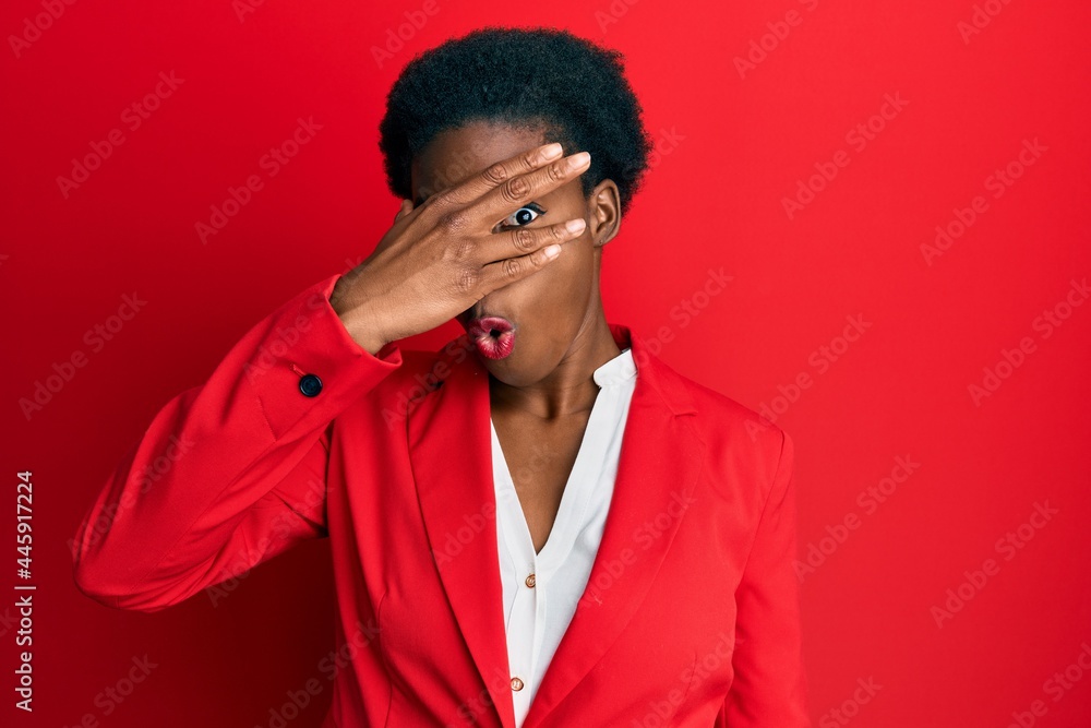 Young african american girl wearing business clothes peeking in shock covering face and eyes with hand, looking through fingers with embarrassed expression.