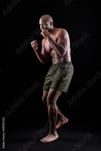 Side view of a muscular adult male standing in defensive boxing pose 