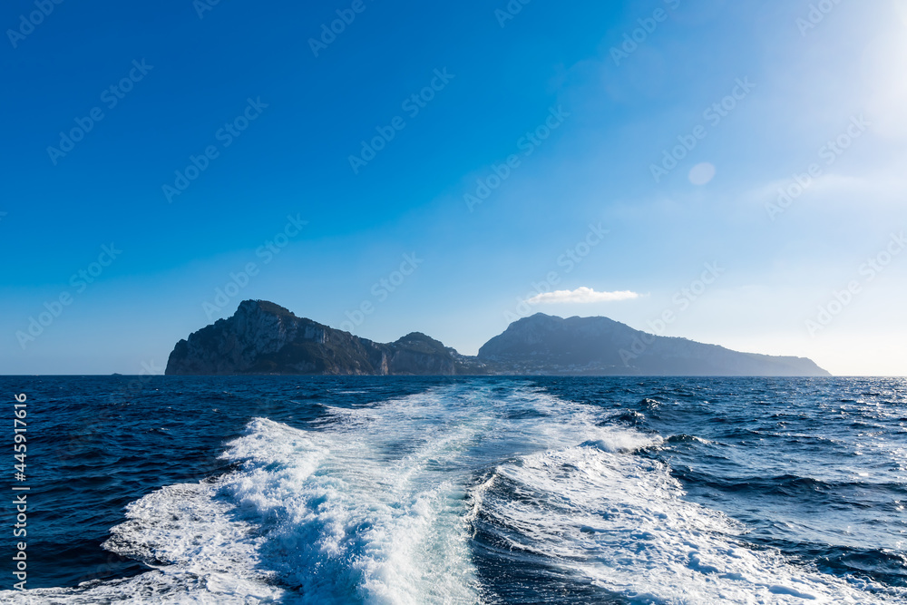 Silhouette of Capri island on Thrrhenian Sea in Italy seen from boat with waves behind