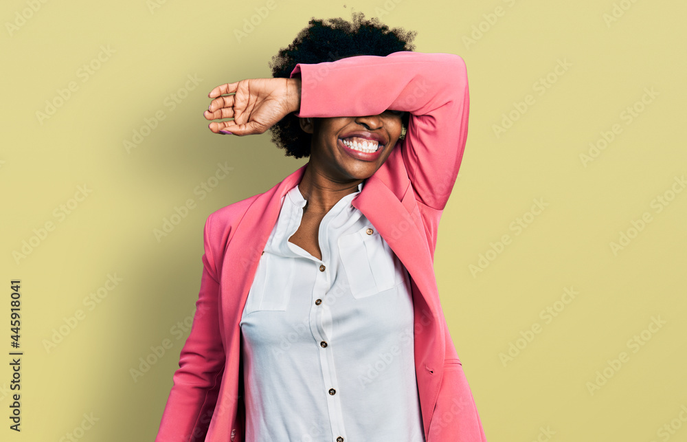 African american woman with afro hair wearing business jacket covering eyes with arm smiling cheerful and funny. blind concept. African american woman with afro hair wearing business jacket covering eyes with arm smiling cheerful and funny. blind concept.