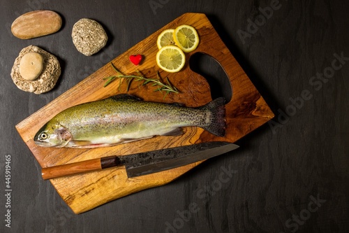 Raw trout on a black wooden table. Home preparation of trout.Healthy diet food. Fresh fish ready for grilling. Fishing industry.